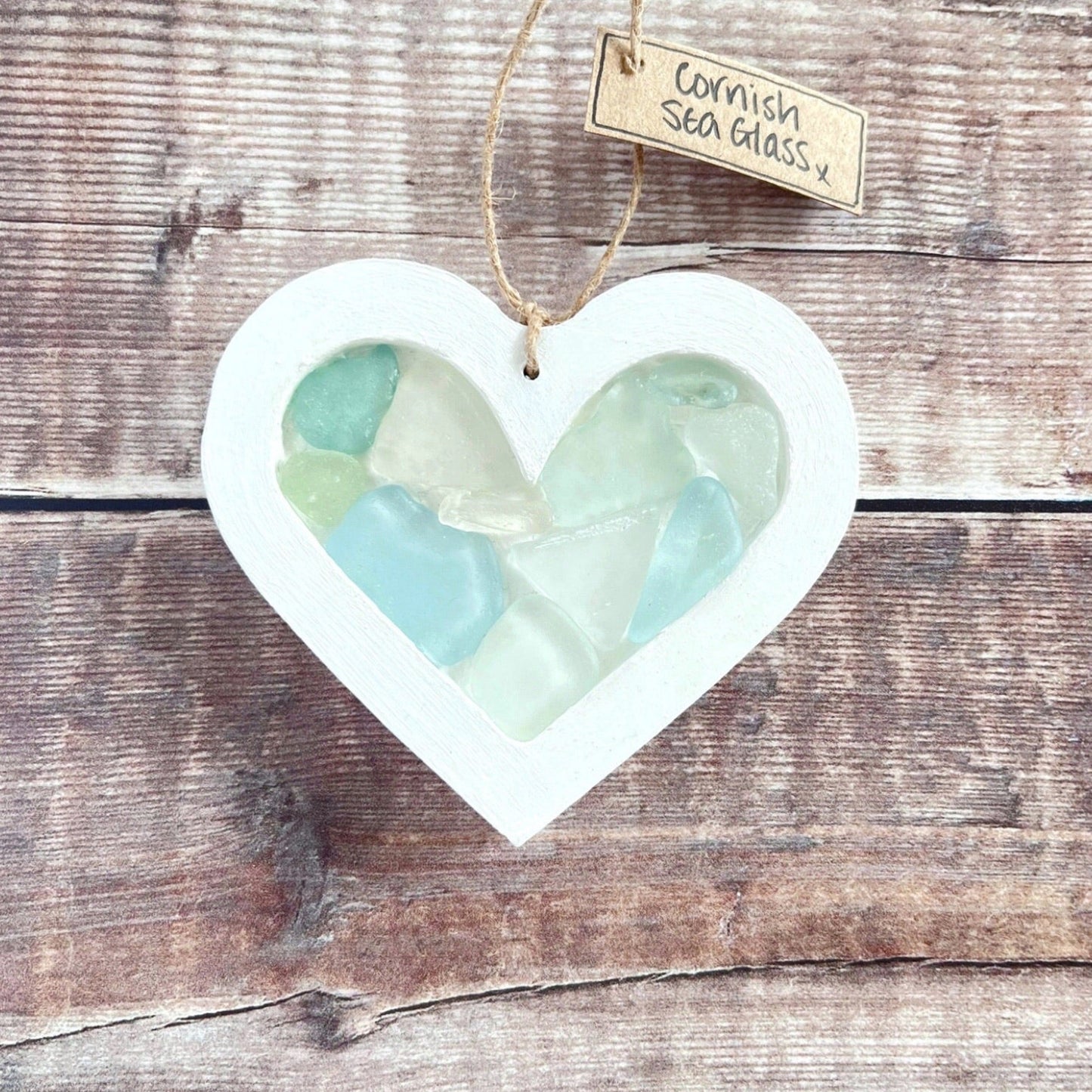 Heart-shaped sea glass hanging decoration with a 'Cornish Sea Glass' tag on a wooden surface