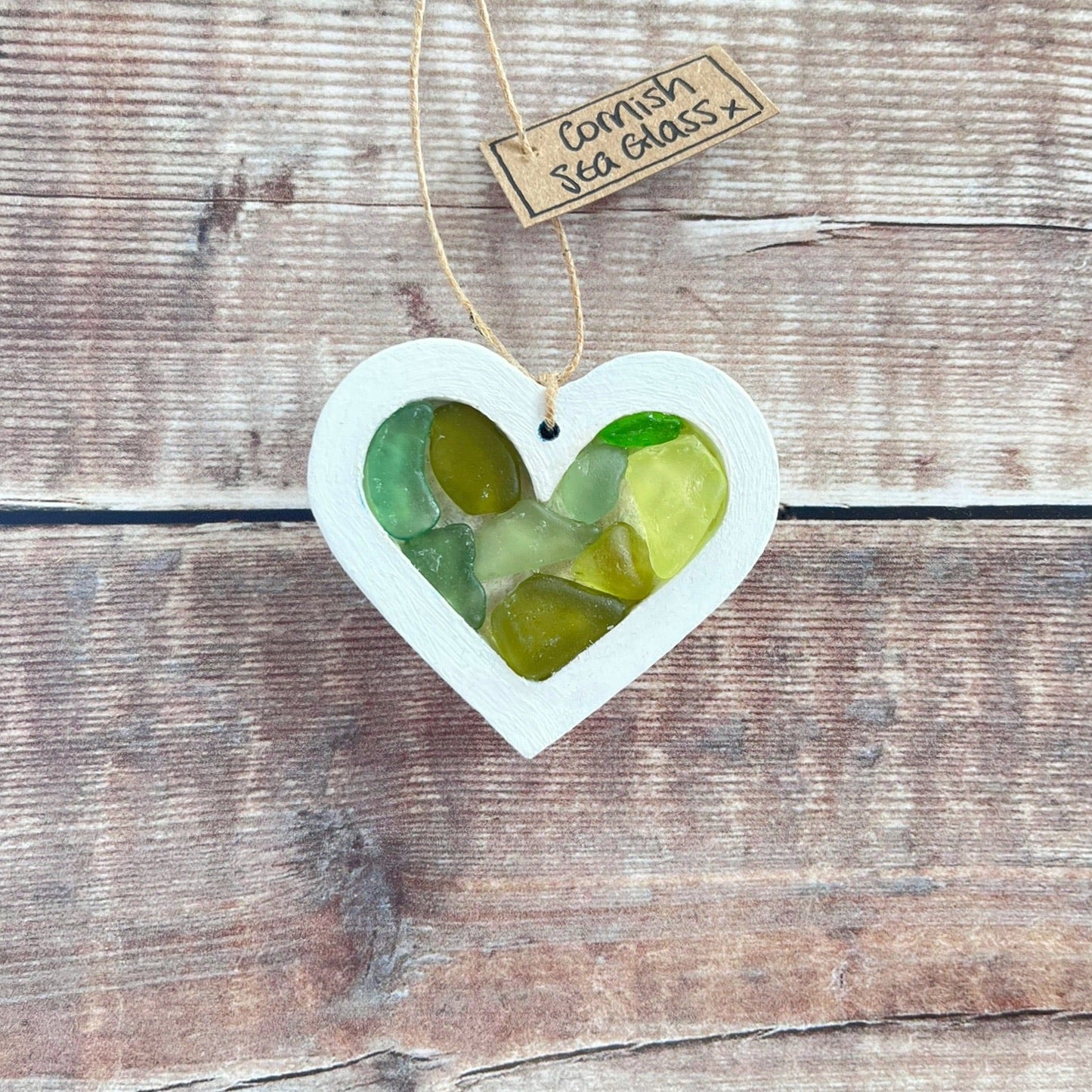 Heart-shaped sea glass hanging decoration with a 'Cornish Sea Glass' tag on a wooden surface