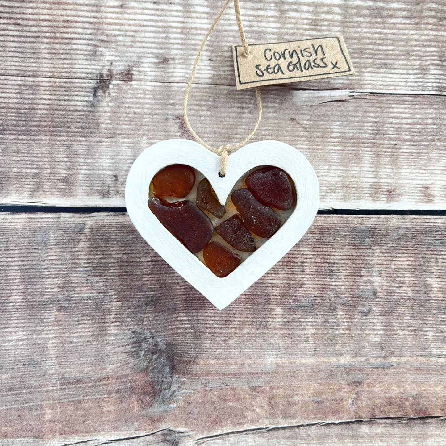 Heart-shaped sea glass hanging decoration with a 'Cornish Sea Glass' tag on a wooden surface