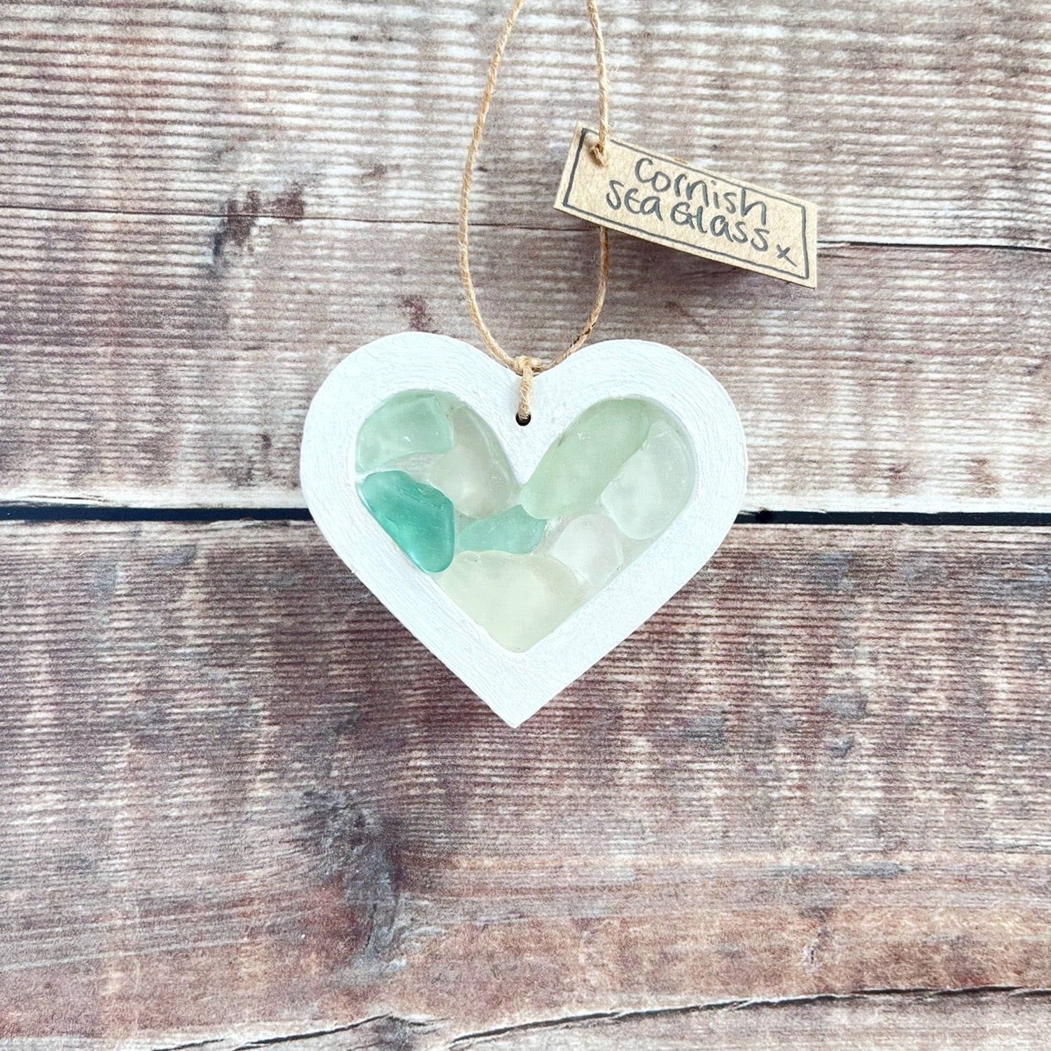 Heart-shaped sea glass hanging decoration with a 'Cornish Sea Glass' tag on a wooden surface