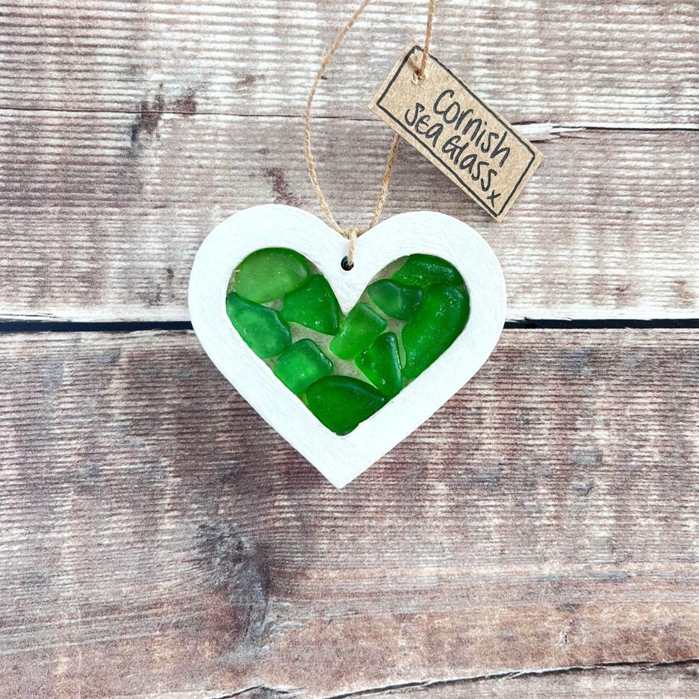 Heart-shaped sea glass hanging decoration with a 'Cornish Sea Glass' tag on a wooden surface