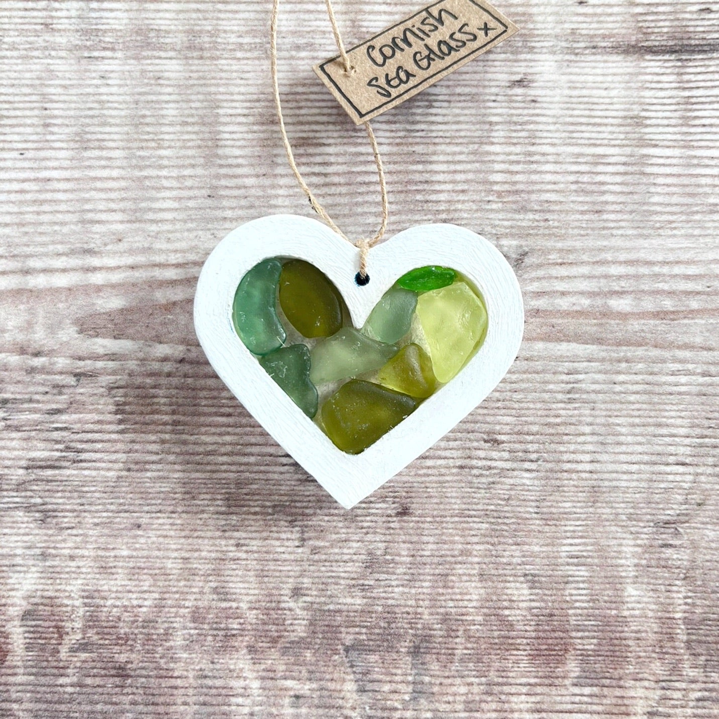 Heart-shaped sea glass hanging decoration with a 'Cornish Sea Glass' tag on a wooden surface