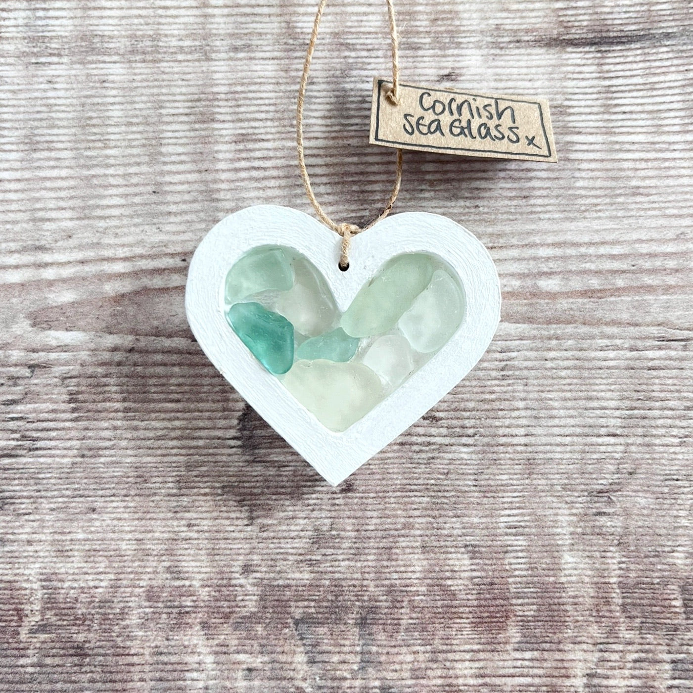 Heart-shaped sea glass hanging decoration with a 'Cornish Sea Glass' tag on a wooden surface