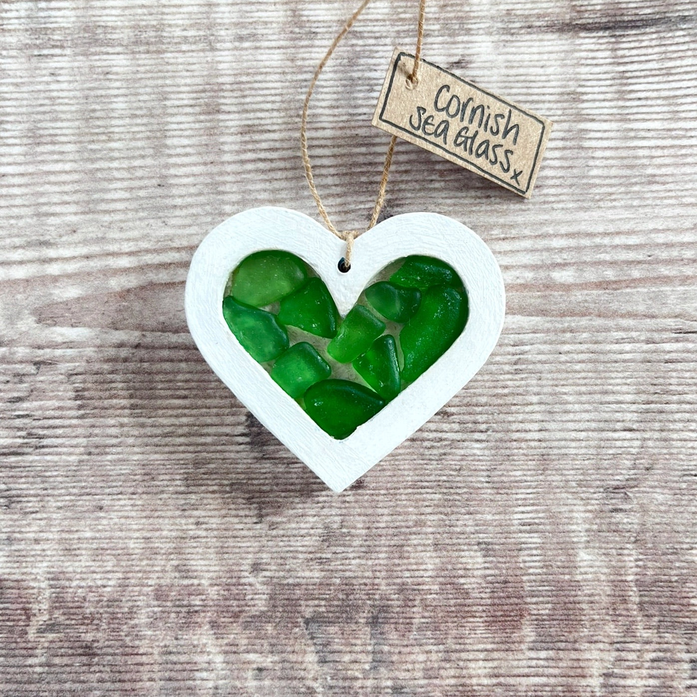 Heart-shaped sea glass hanging decoration with a 'Cornish Sea Glass' tag on a wooden surface
