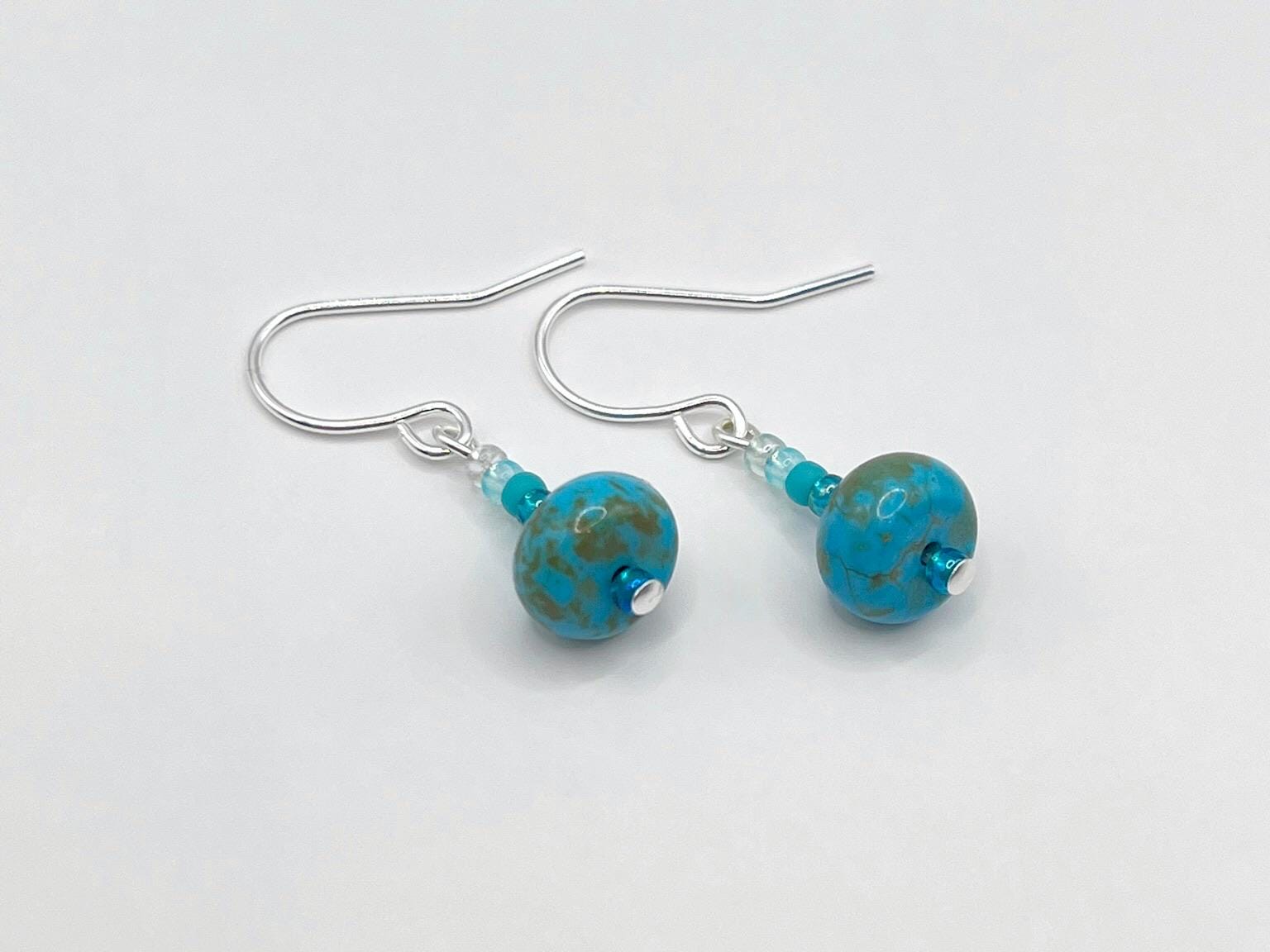 Pair of turquoise beaded earrings on a white background