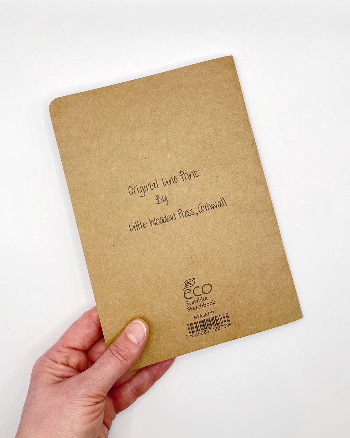 Kraft paper notebook held by a hand on a white background