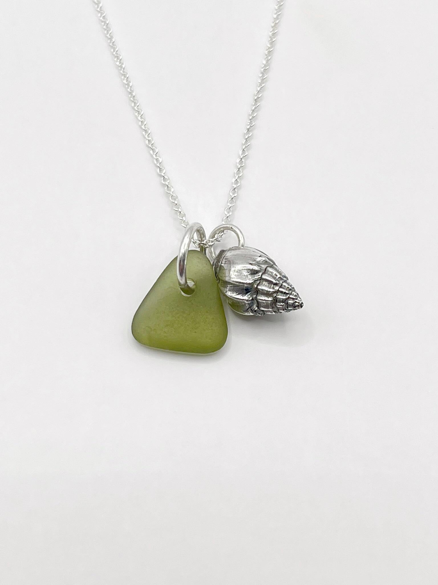 Necklace with olive green sea glass and a silver shell pendant laid on a white background