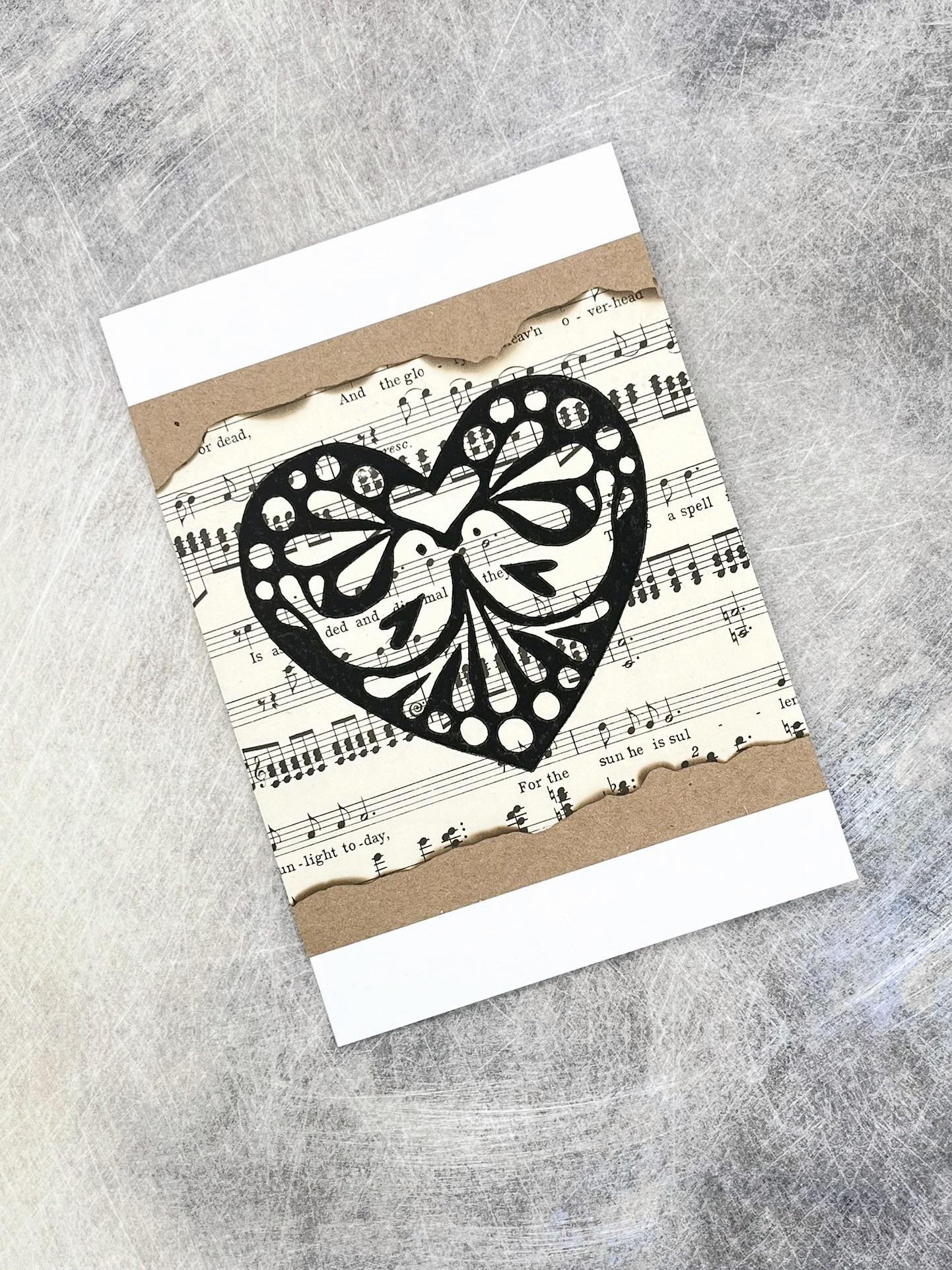 Card with black heart design on sheet music background