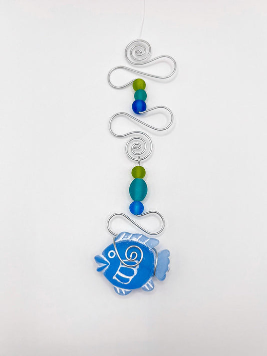Decorative hanging ornament with blue fish, wire and colourful beads on a white background
