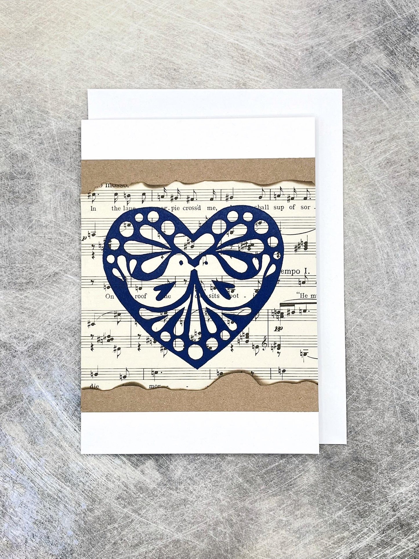 Card with blue heart design on sheet music against a textured background