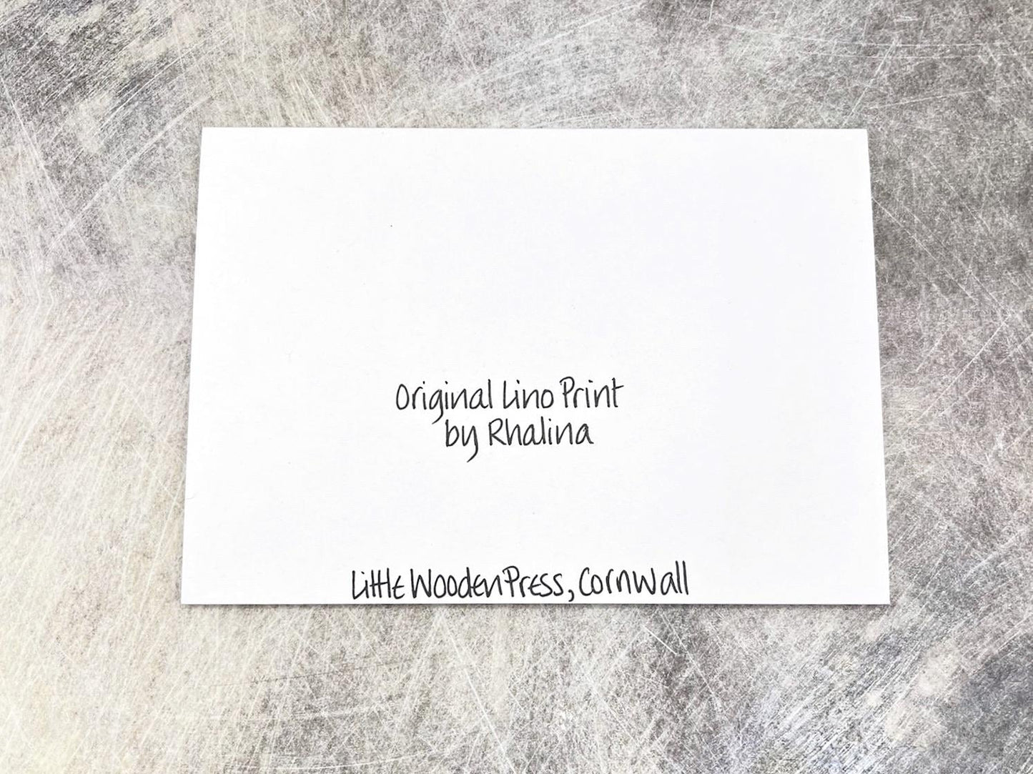 Back of the white card with black text laid on a textured grey background