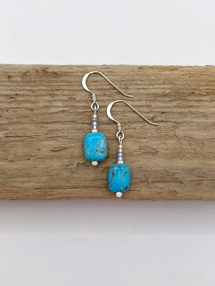 Turquoise beaded earrings on a wooden surface