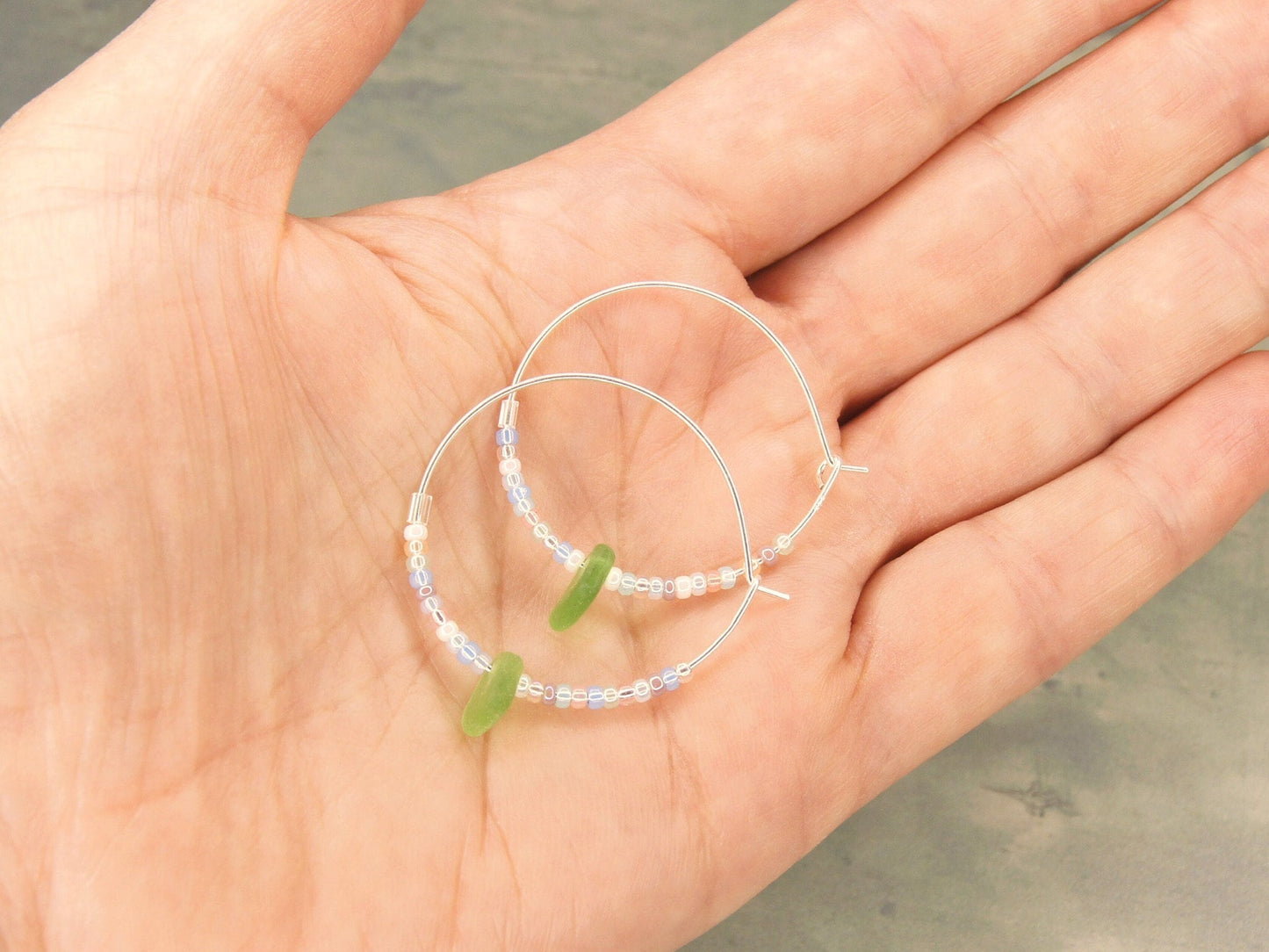 Pair of hoop earrings with beads on a hand