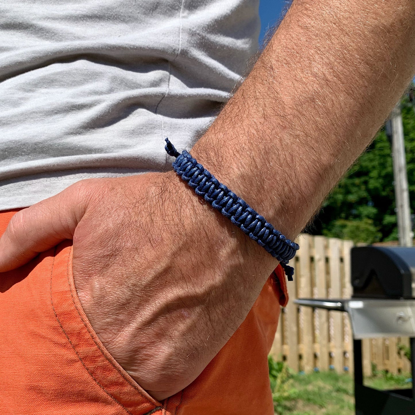 Person wearing a blue macrame bracelet with a blurred outdoor background