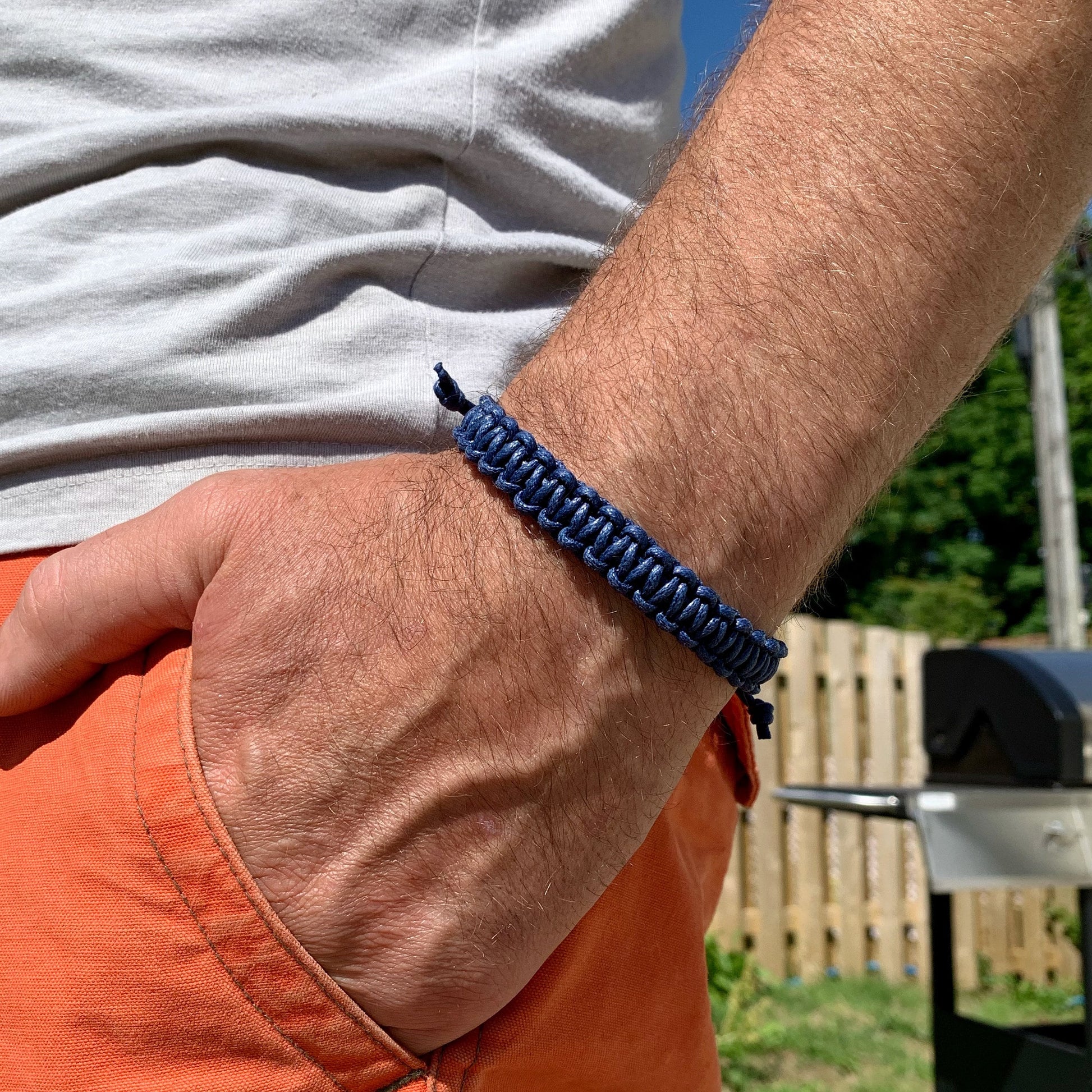 Person wearing a blue macrame bracelet with a blurred outdoor background