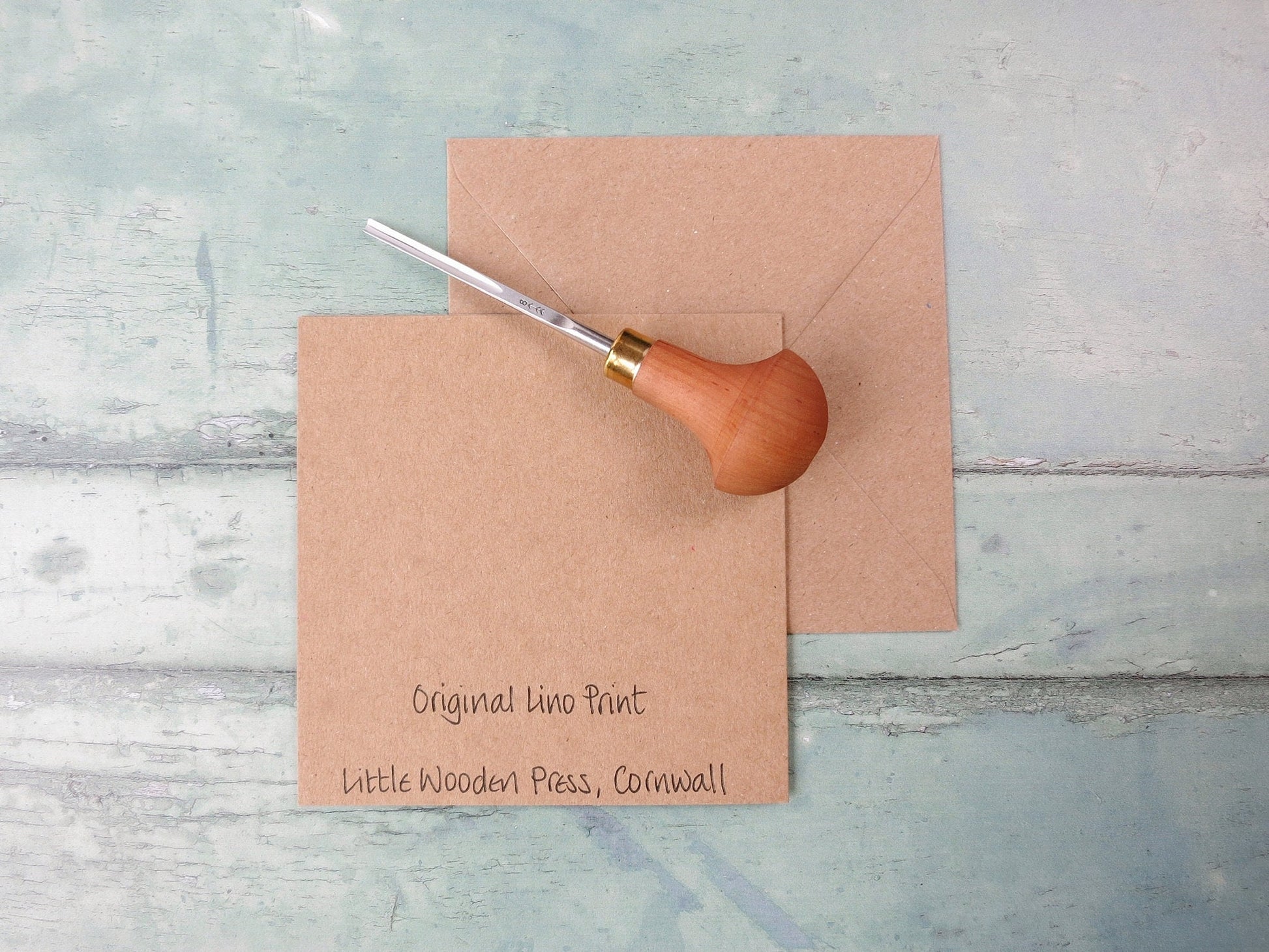 Showing the back of the card with text and matching Kraft envelope. Photo includes lino cutting tool