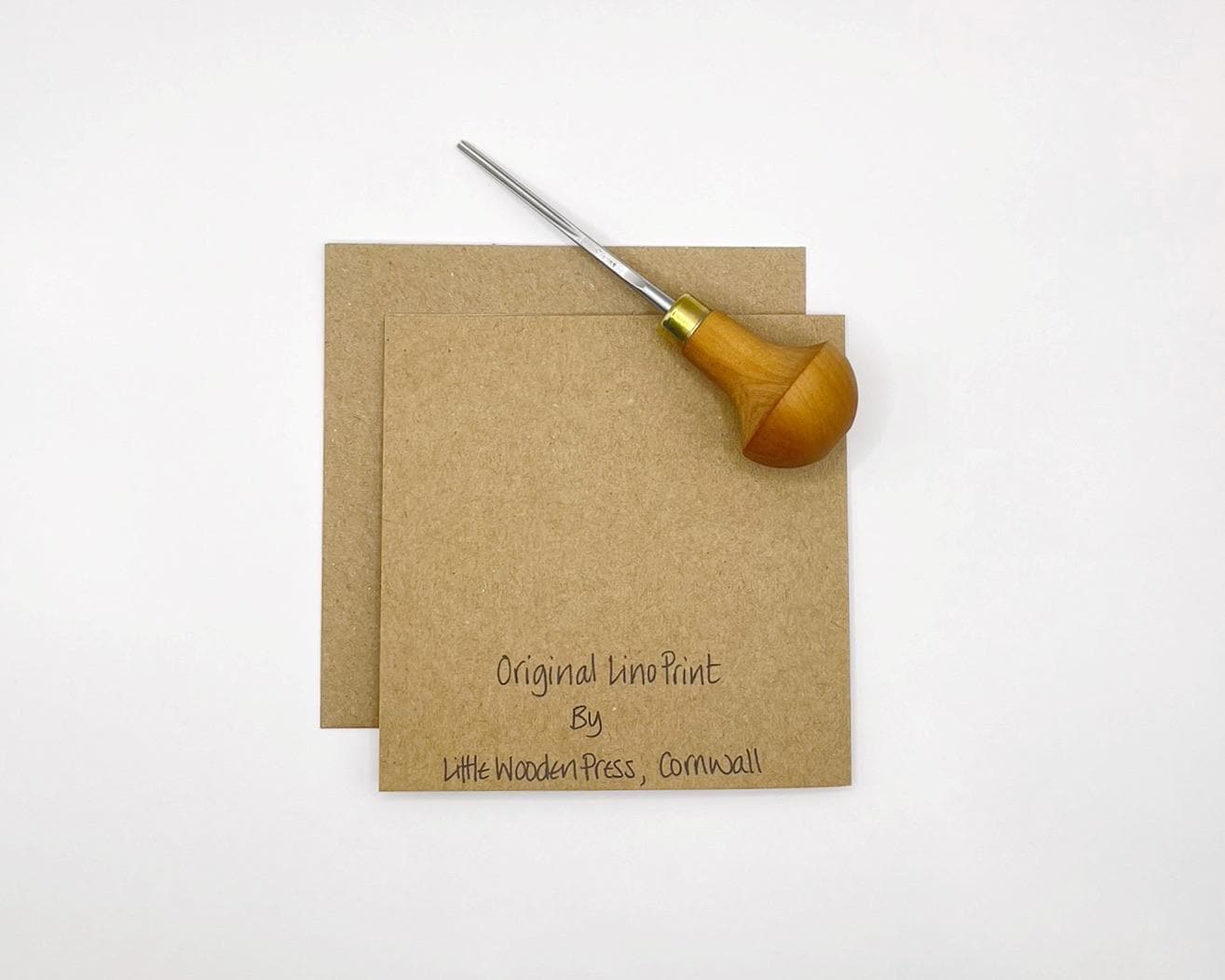 Showing the back of the Kraft paper card laid on a white background. Photo includes lino cutting tool.