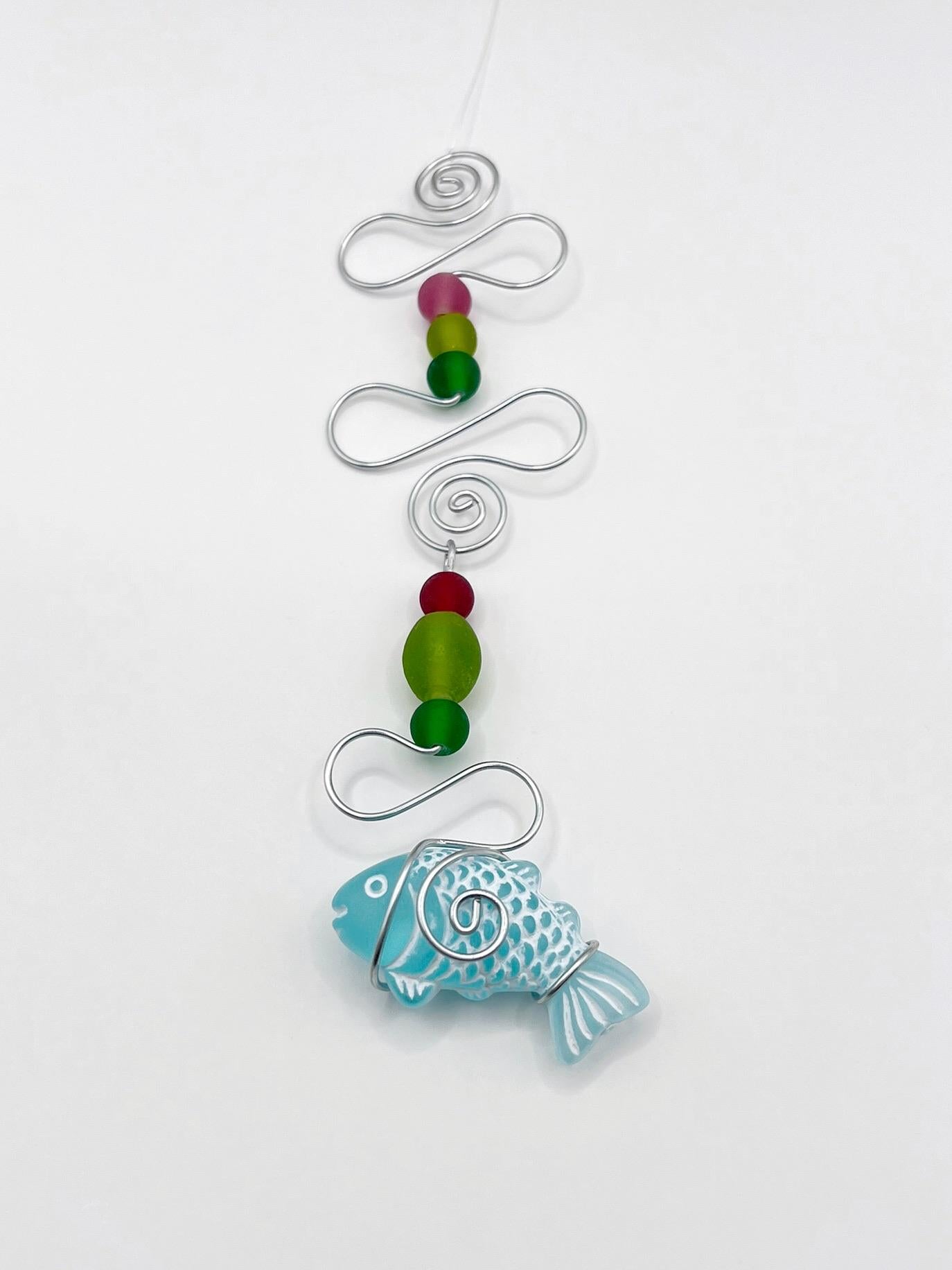 Decorative hanging ornament with a fish design, wire and colourful beads on a white background