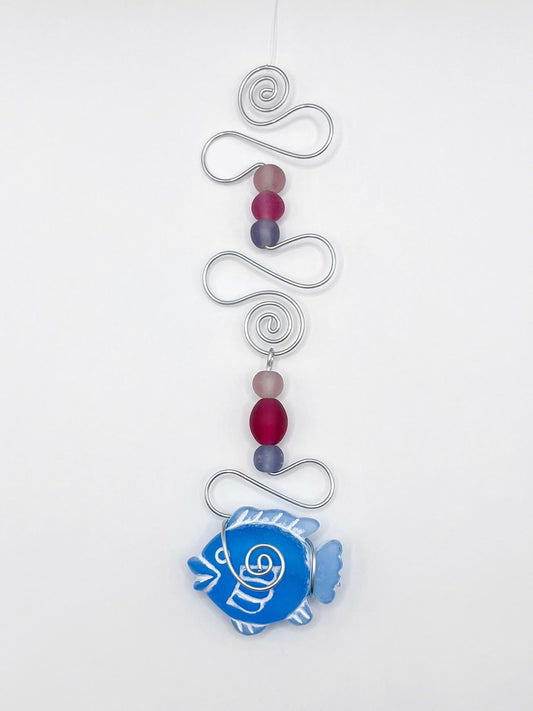 Decorative ornament with blue fish, wire and colourful beads on a white background