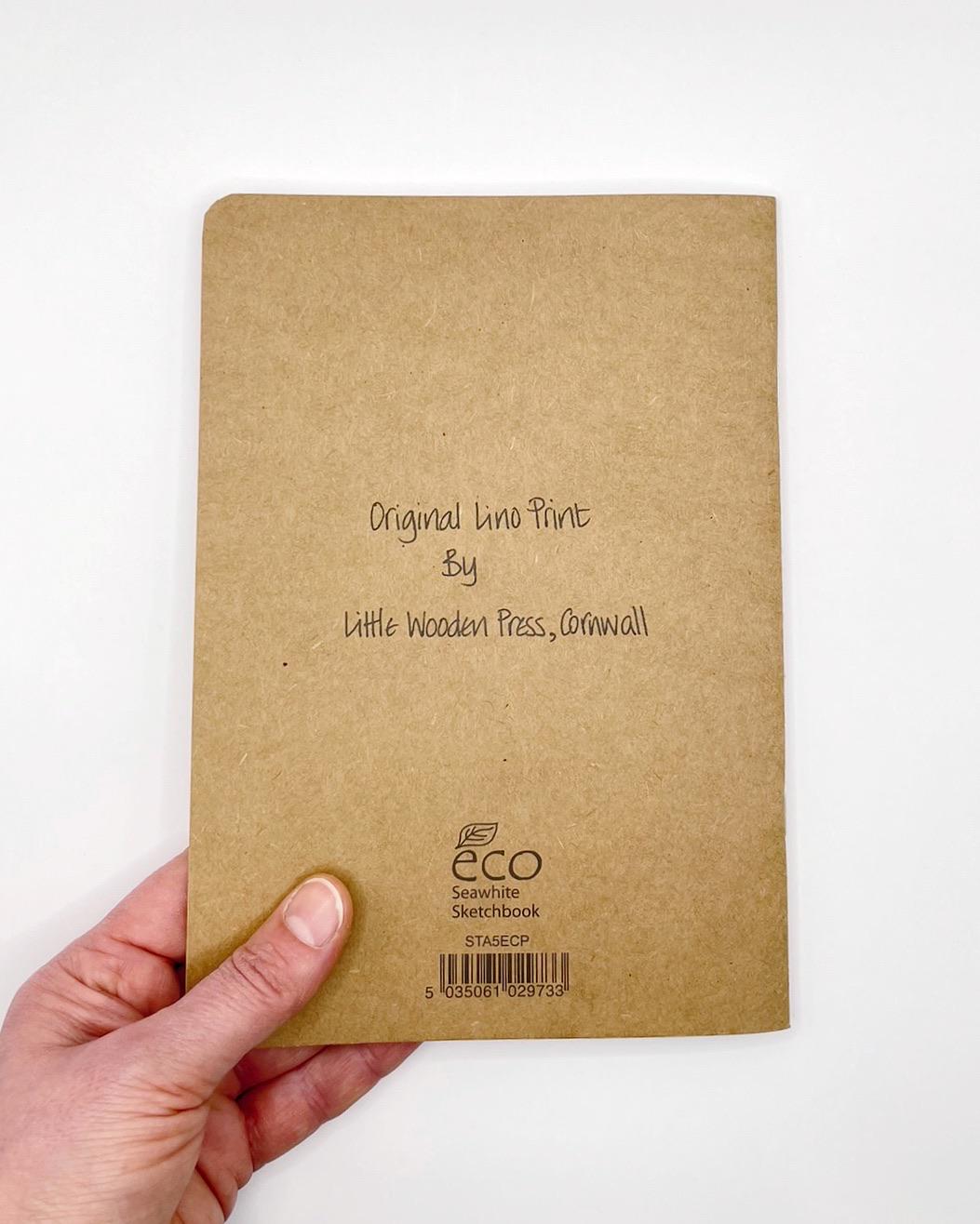 Hand holding a brown notebook with 'eco' branding on a white background