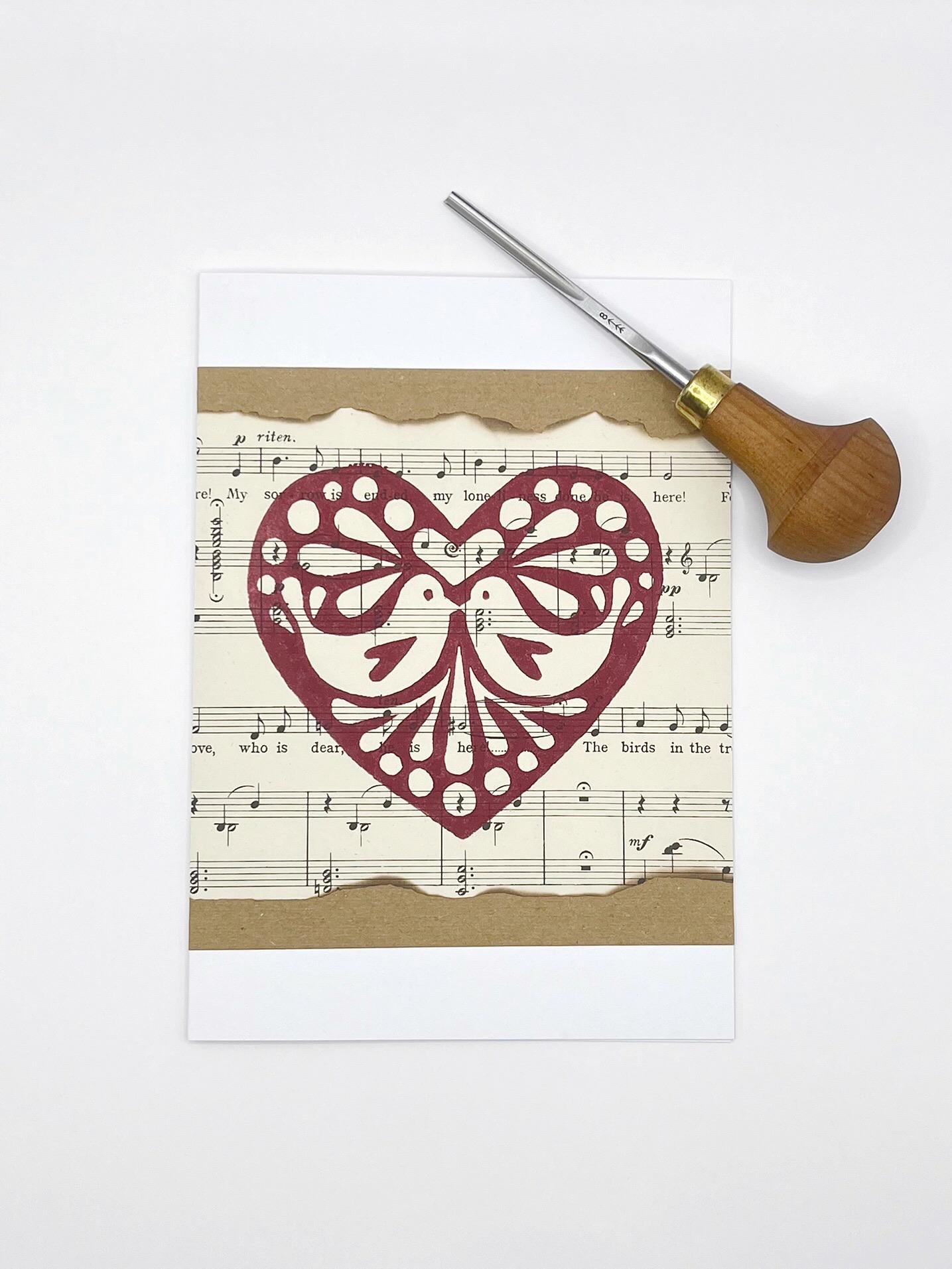 Card with original lino printed heart design on sheet music. Photo includes the lino cutting tool used.