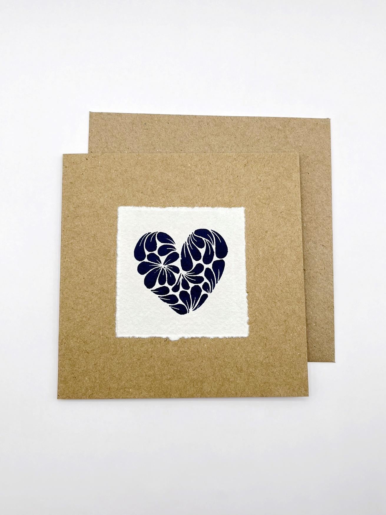 Kraft card with original lino printed blue heart design on white paper with matching Kraft envelope laid on a white background