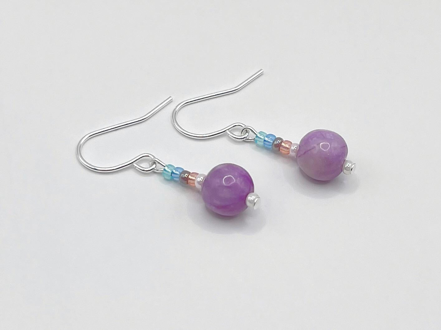 Pair of pastel seed bead and lilac jasper earrings laid on a white background.