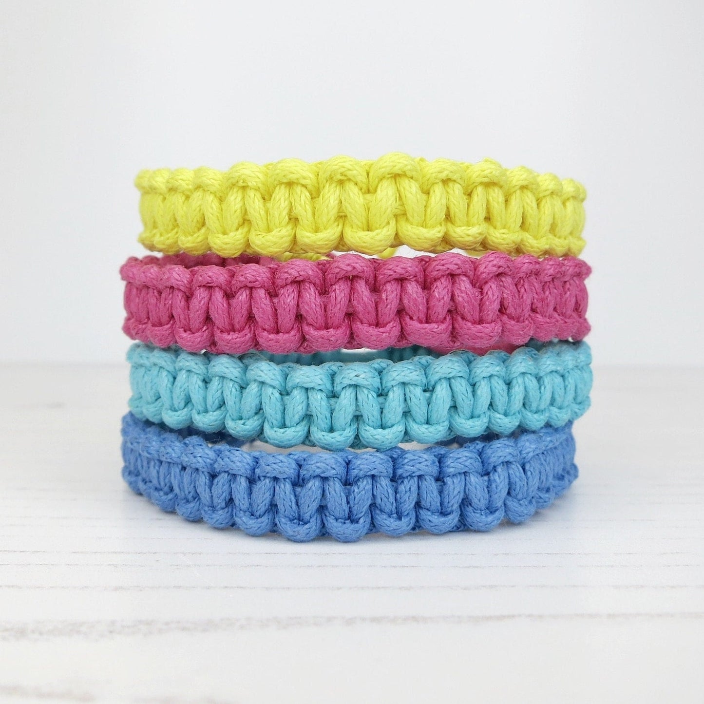 Stack of colourful macrame bracelets on a white background