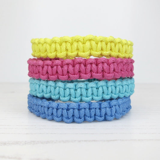 Stack of colourful macrame bracelets on a white background