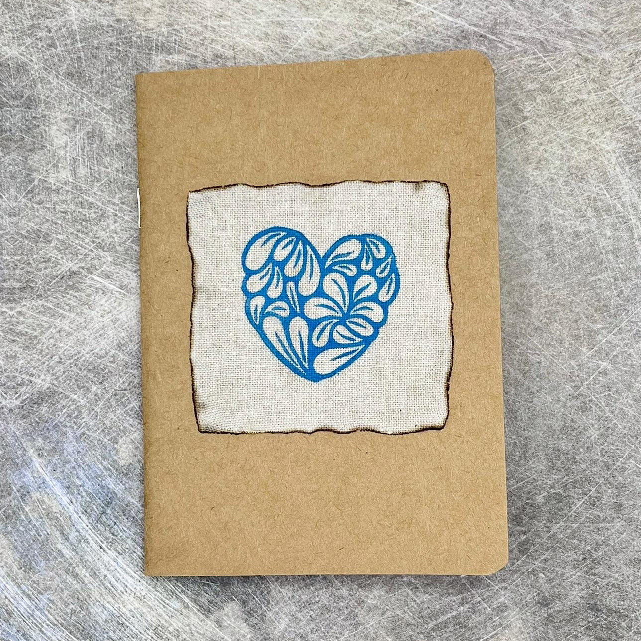 A6 Kraft notebook with blue heart design on a textured surface
