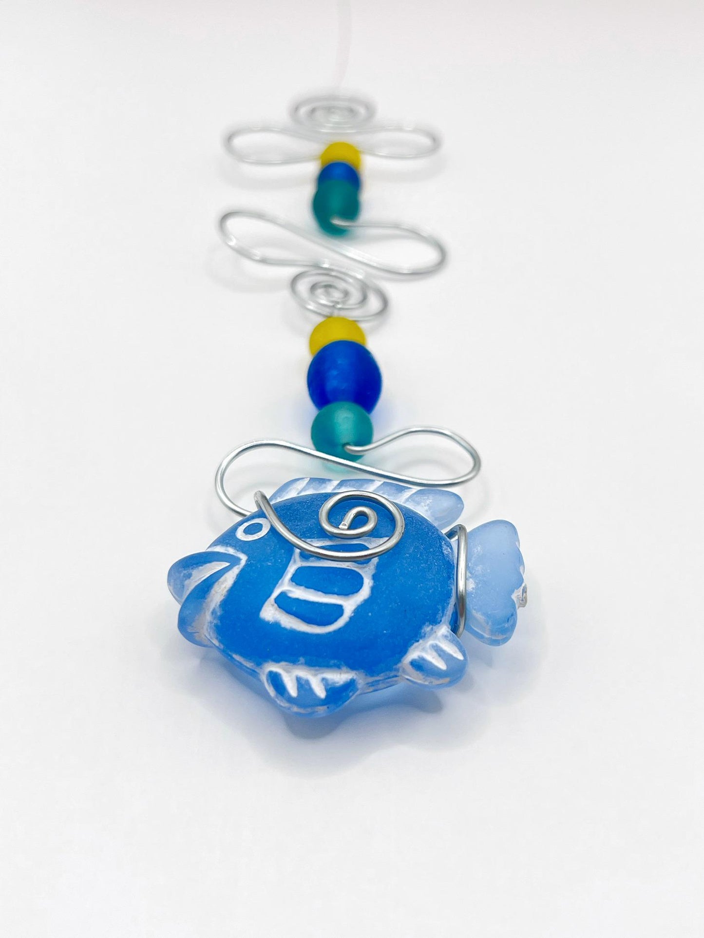 Decorative ornament with blue fish design, wire and colourful beads on a white background