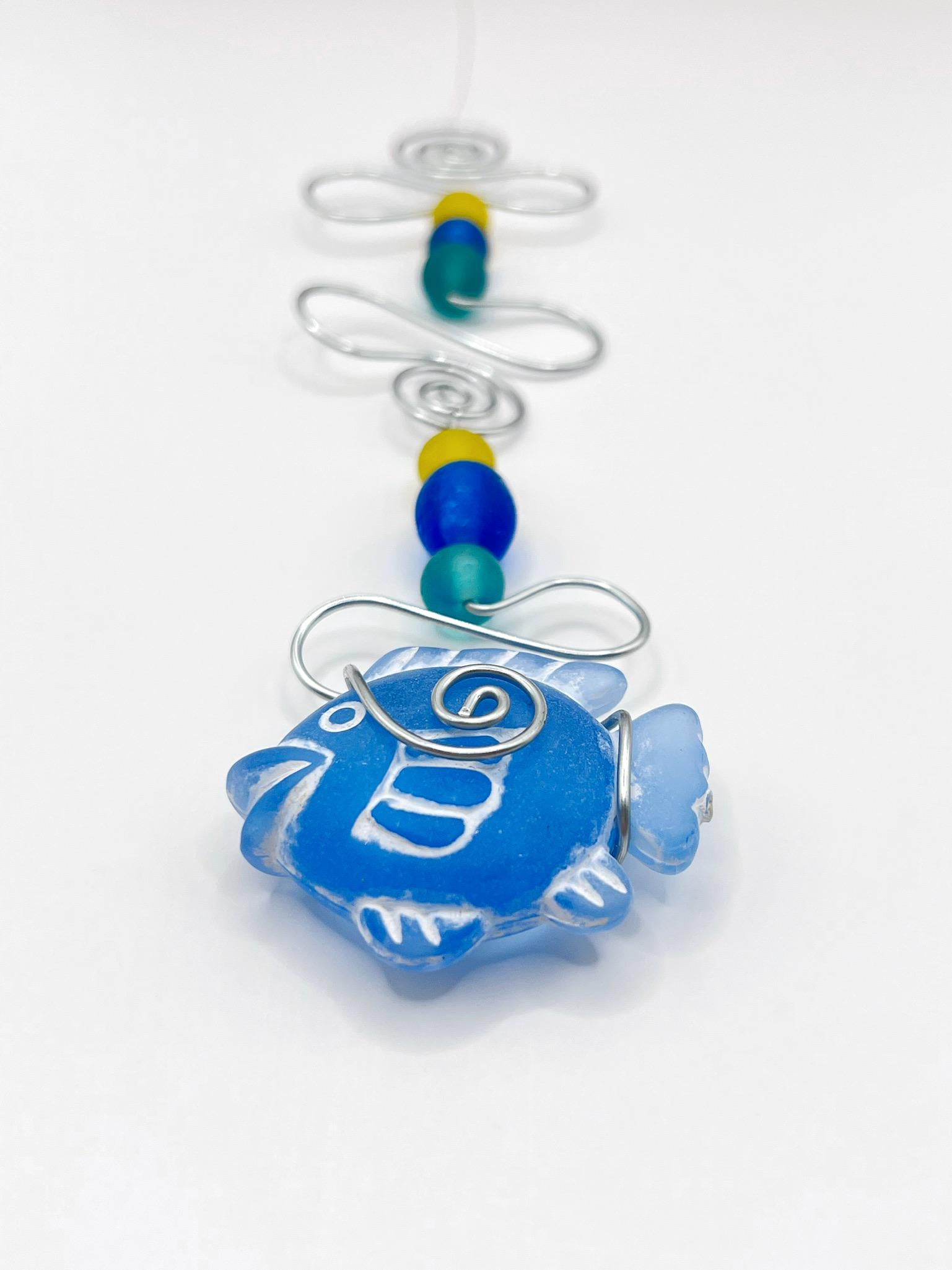 Decorative ornament with blue fish design, wire and colourful beads on a white background