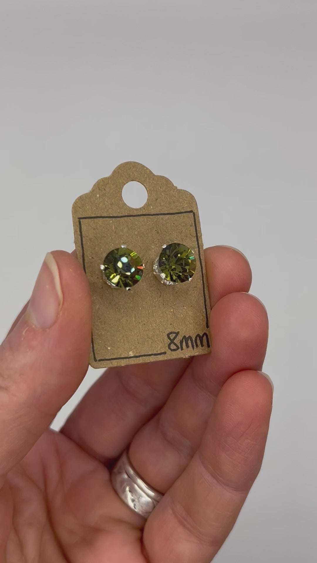 Video of cut glass stud earrings on a backing card, held in hand and moving to show the sparkle.