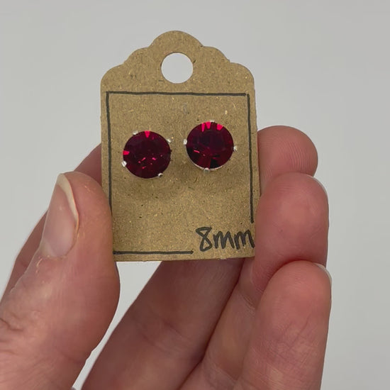 Video of cut glass stud earrings on a backing card, held in hand and moving to show the sparkle.