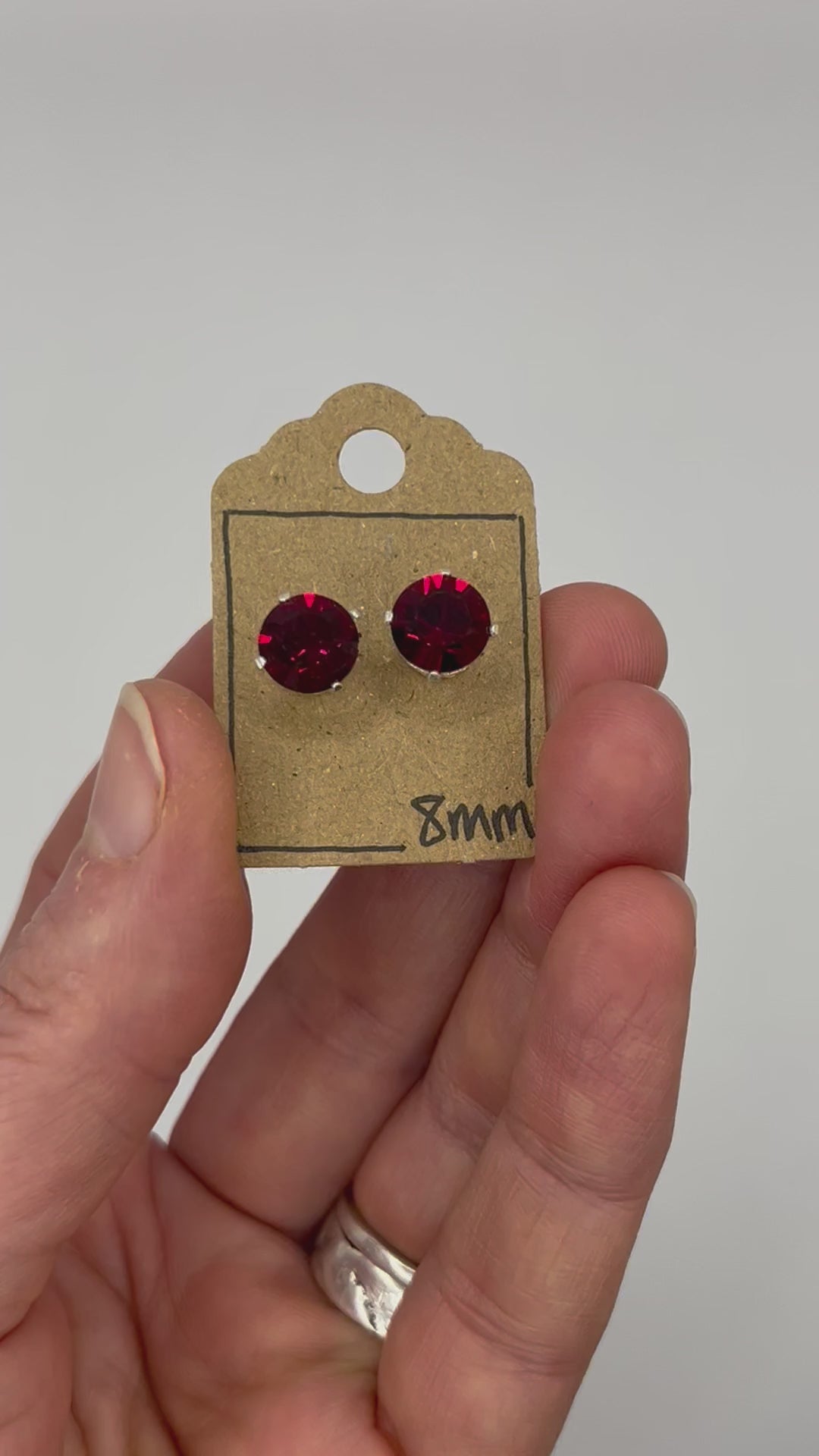 Video of cut glass stud earrings on a backing card, held in hand and moving to show the sparkle.