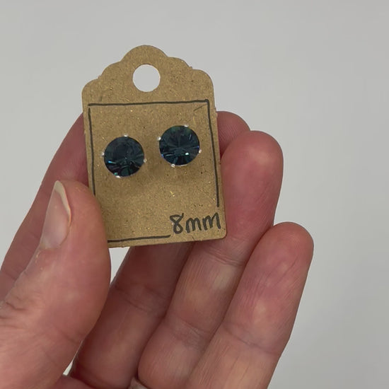 Video of cut glass stud earrings on a backing card, held in hand and moving to show the sparkle.