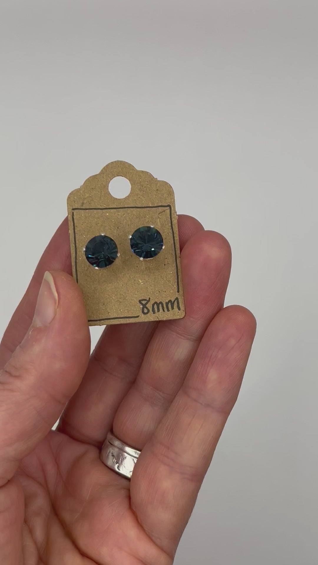 Video of cut glass stud earrings on a backing card, held in hand and moving to show the sparkle.