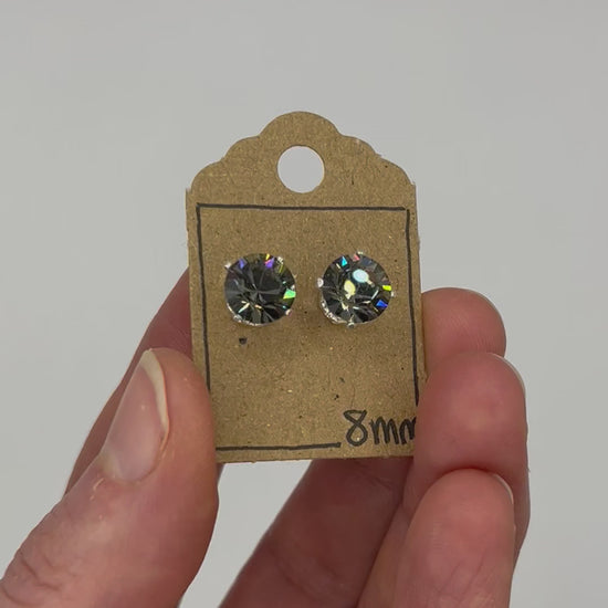 Video of cut glass stud earrings on a backing card, held in hand and moving to show the sparkle.