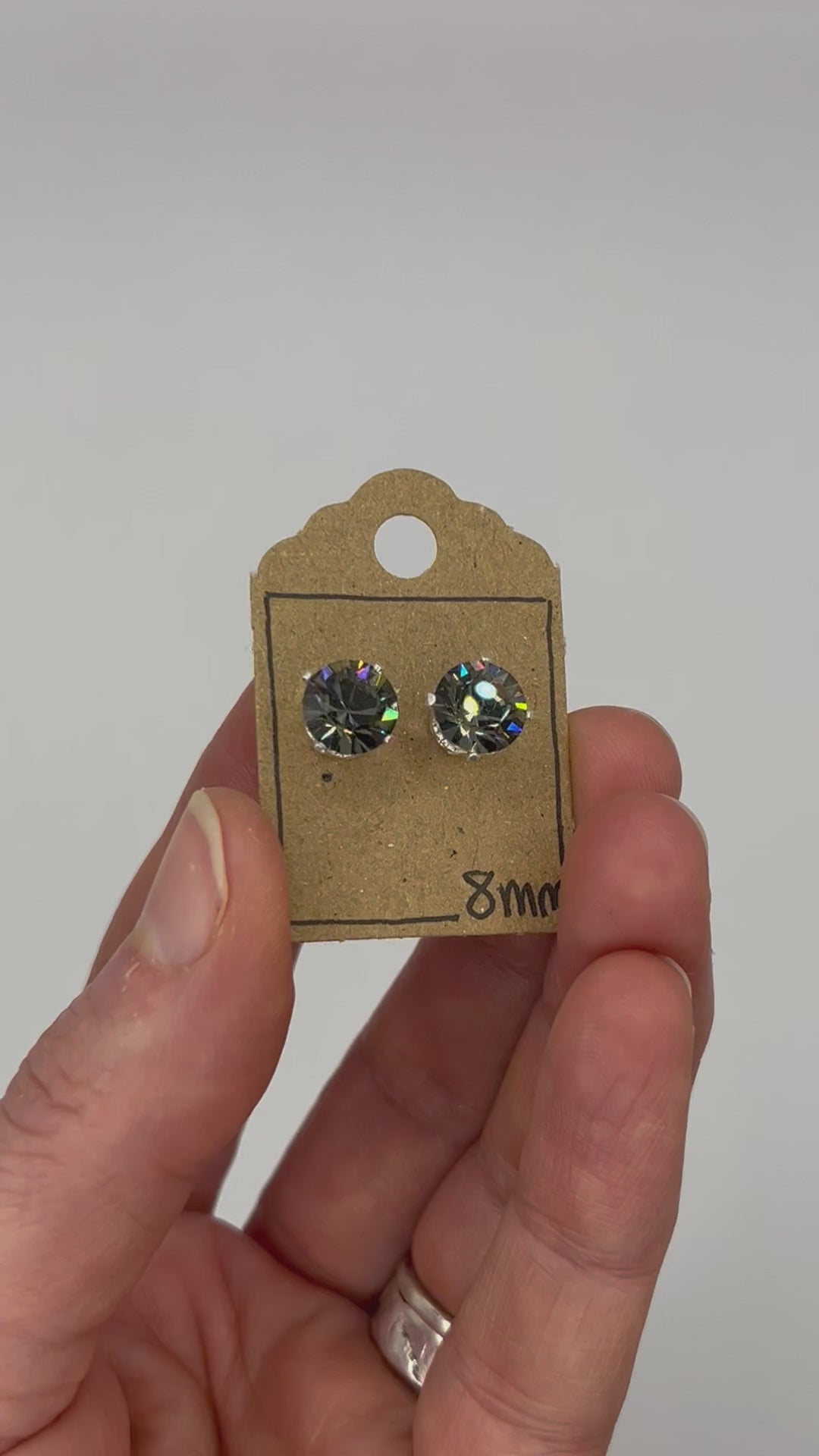 Video of cut glass stud earrings on a backing card, held in hand and moving to show the sparkle.