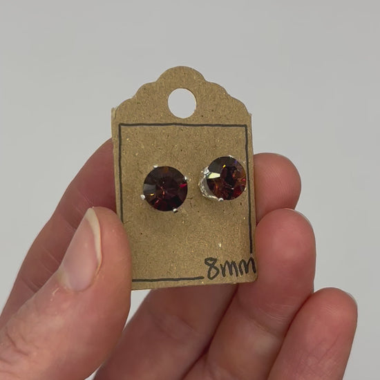 Video of cut glass stud earrings on a backing card, held in hand and moving to show the sparkle.
