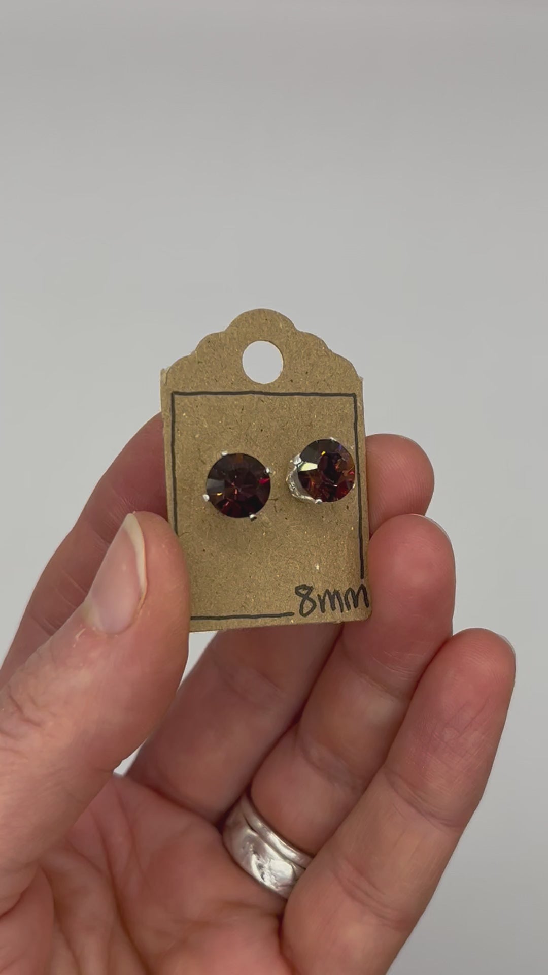 Video of cut glass stud earrings on a backing card, held in hand and moving to show the sparkle.