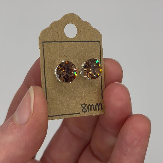 Video of cut glass stud earrings on a backing card, held in hand and moving to show the sparkle.