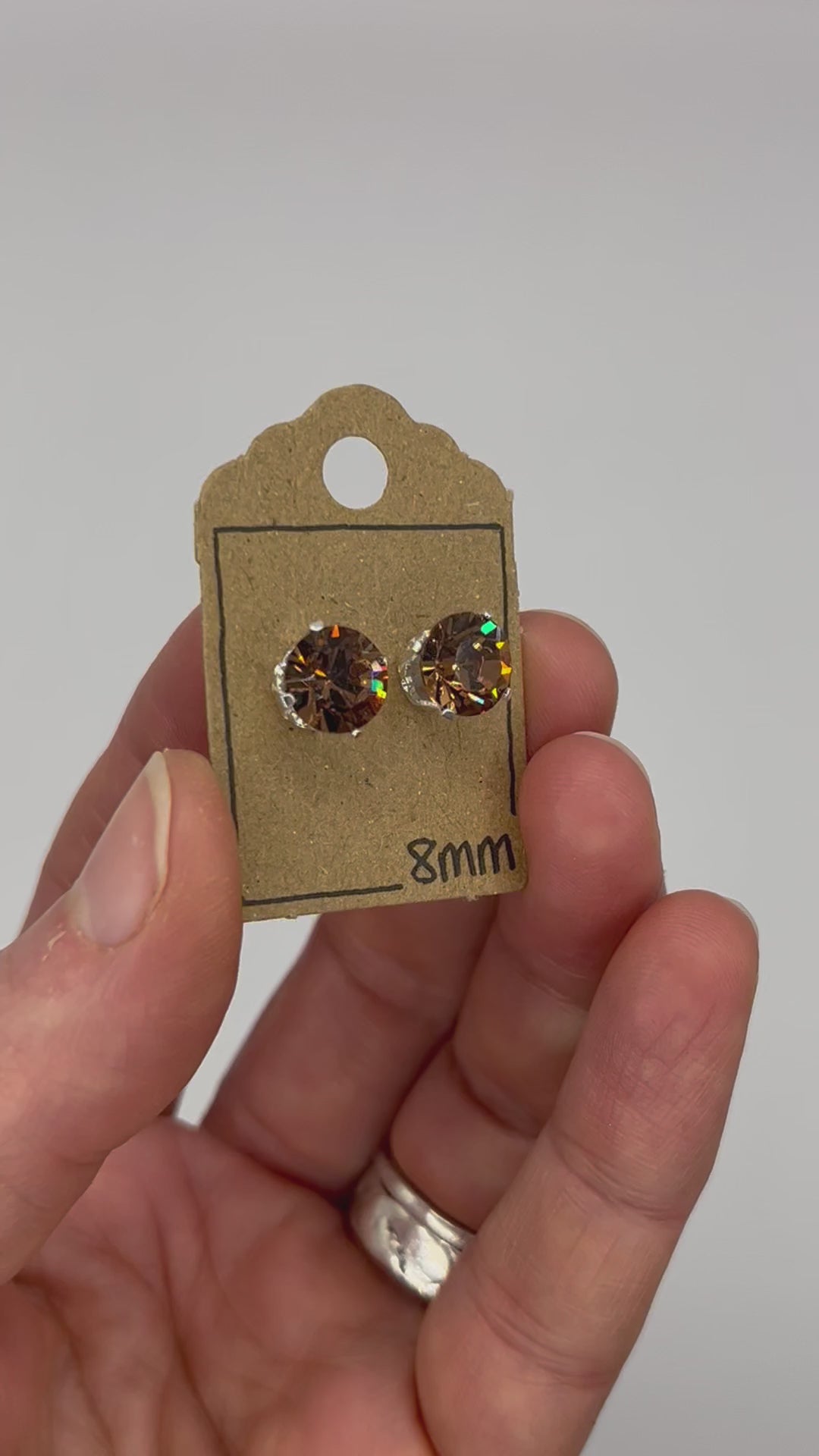 Video of cut glass stud earrings on a backing card, held in hand and moving to show the sparkle.