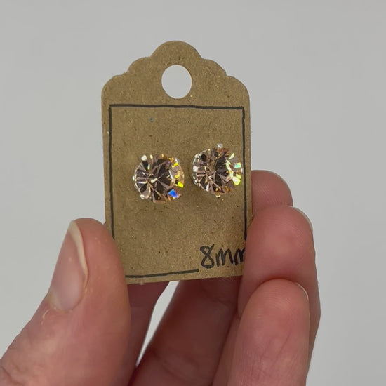 Video of cut glass stud earrings on a backing card, held in hand and moving to show the sparkle.