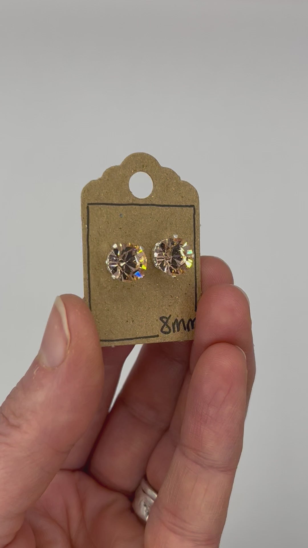 Video of cut glass stud earrings on a backing card, held in hand and moving to show the sparkle.