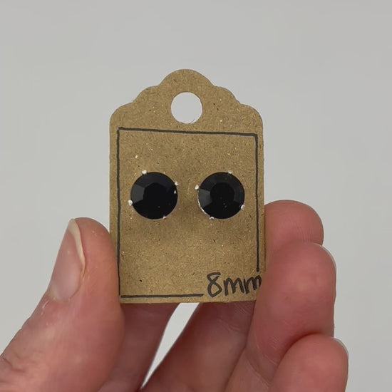 Video of cut glass stud earrings on a backing card, held in hand and moving to show the sparkle.