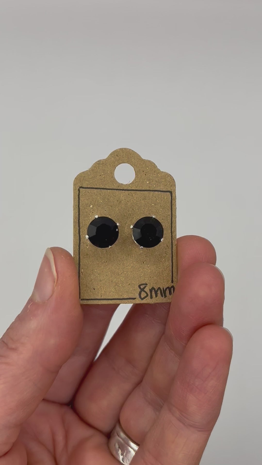 Video of cut glass stud earrings on a backing card, held in hand and moving to show the sparkle.